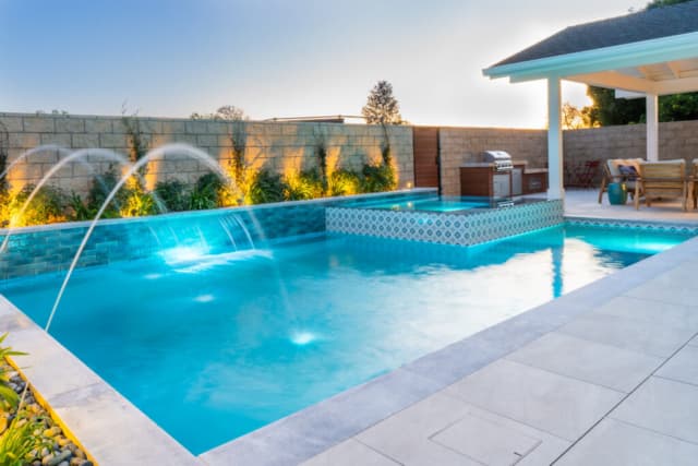 Geometric pool with raised spa and water features at dusk