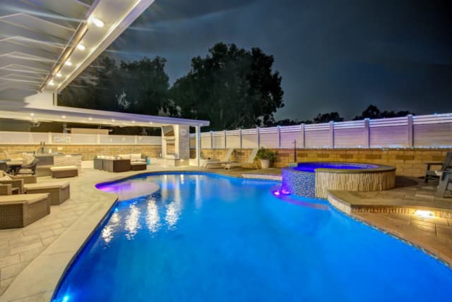 Infinity-edge pool beside a covered patio at sunset
