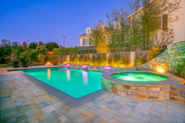 Rectangular pool with circular spa, slide, and stonework