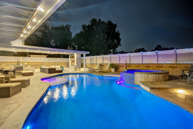 Infinity-edge pool beside a covered patio at sunset